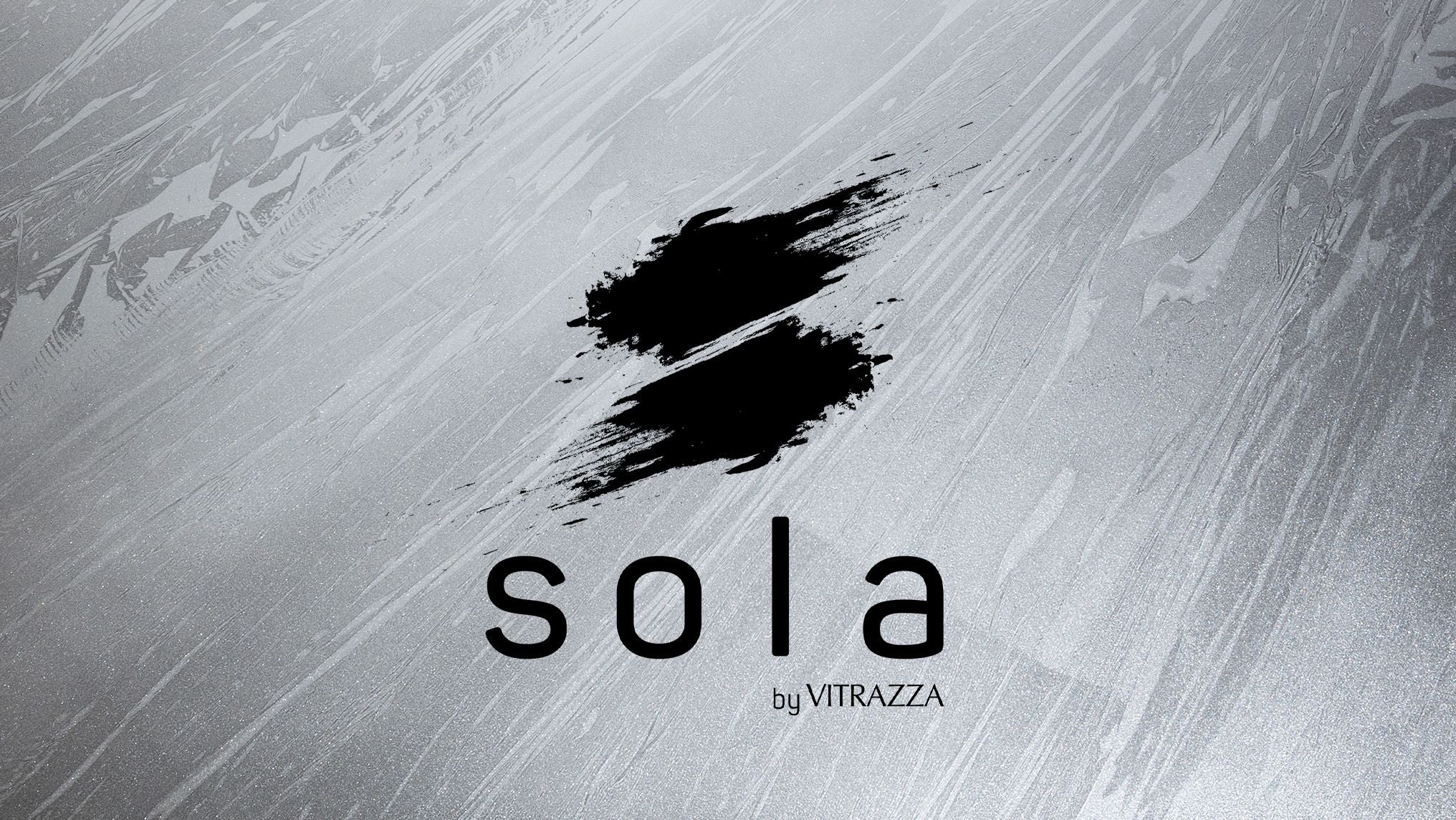 A logo featuring a black brushstroke forming an "S" shape on a textured gray background. Below the brushstroke, the word "sola" is written in bold, black letters, and underneath "sola," the text "by VITRAZZA" is displayed in smaller black letters.